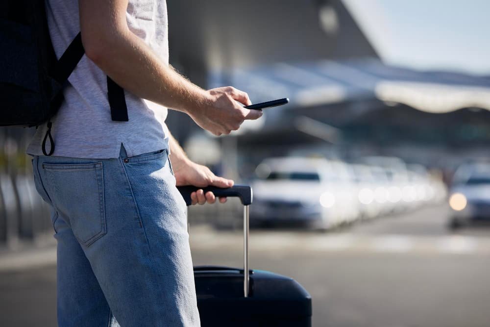 Un homme tenant un smartphone devant aeoroport